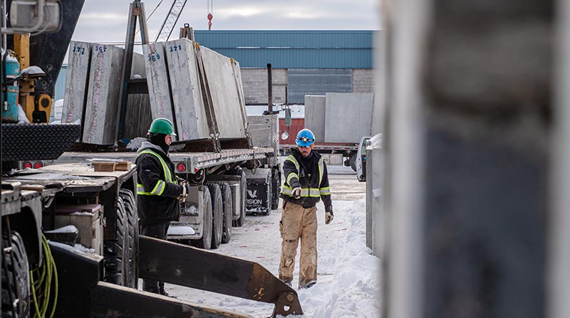 Crew unloading precast concrete panels from a flatbed truck
